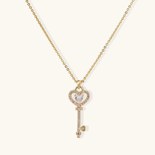 Gold necklace with a heart-shaped key pendant on a white background