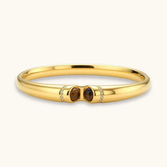 Gold bracelet with two brown gemstones on a white background